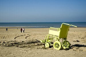 Yellow beach wheelchair in front of the sea