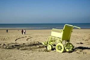 Yellow beach wheelchair in front of the sea